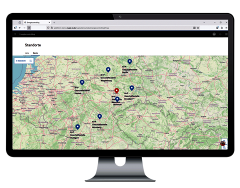 Monitor mit Kartenansicht im Energiecontrolling, auf der mehrere Standorte als Pins markiert sind.